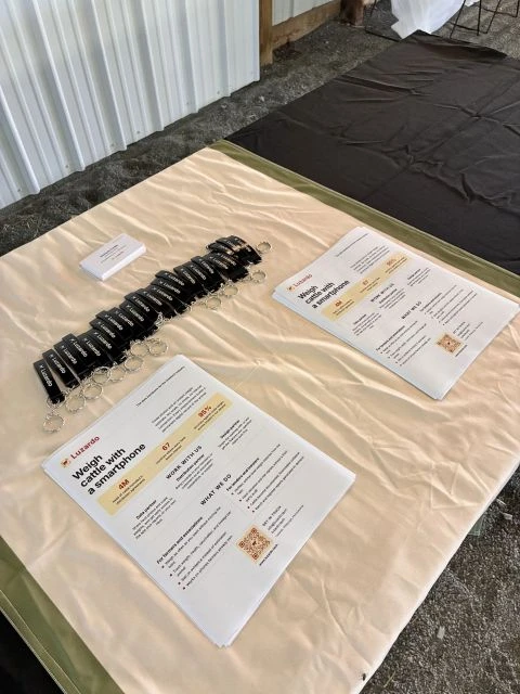 Luzardo leaflets reading “Weigh cattle with a smartphone” laid out with branded keyrings on the booth table